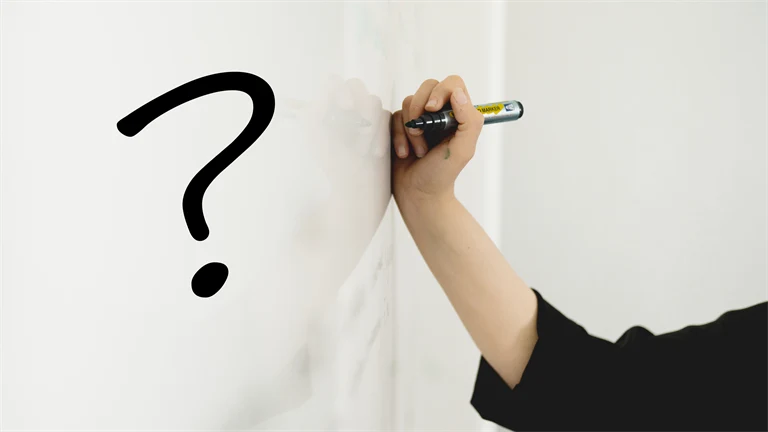 Hand ritar ett frågetecken med svart penna på whiteboardtavla