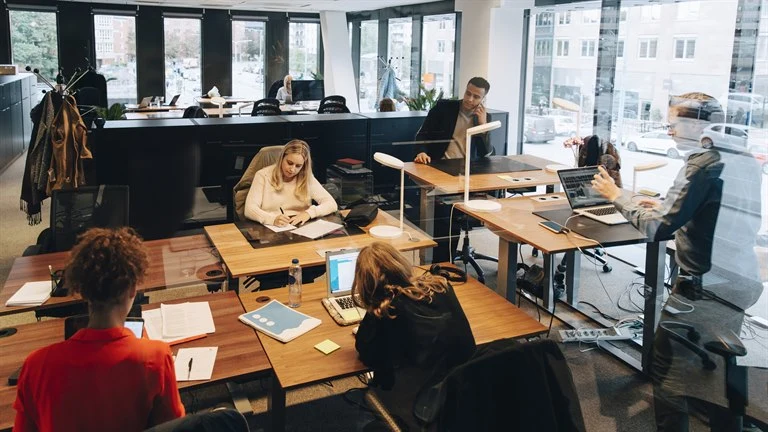 Medarbetare arbetar koncentrerat runt skrivbord på kontor